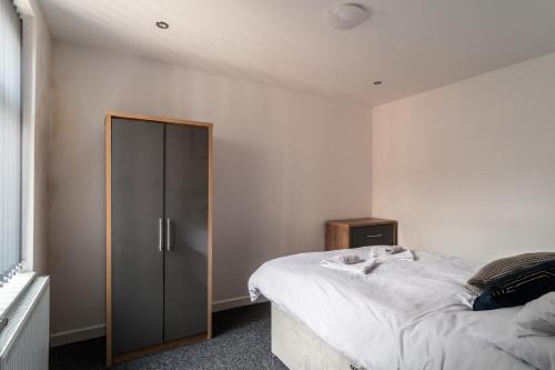 a bedroom with a large bed and a wooden cabinet at Harmony House: Shared Spaces Room 3 in Manchester