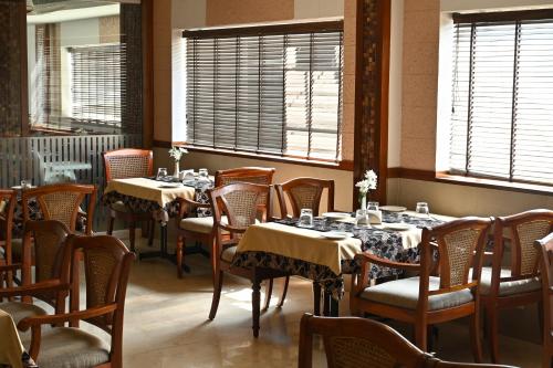 een eetkamer met tafels, stoelen en ramen bij Hotel Royale Park Alleppey in Alleppey