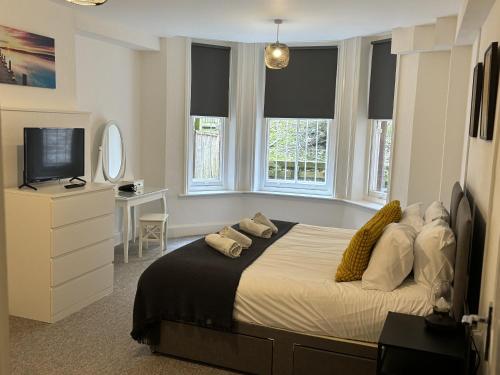 um quarto com uma cama, uma televisão e janelas em Urban Living - Flat 2 em Bournemouth