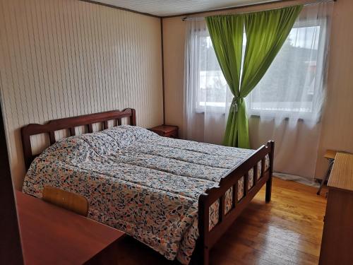 a bedroom with a bed and a window with green curtains at Casa Amoblada en Coronel 2 in Coronel