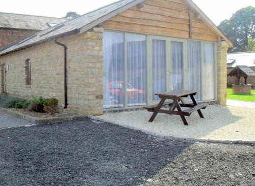 a picnic table sitting in front of a building at Foxes Den at Tove Valley Cottages in Towcester