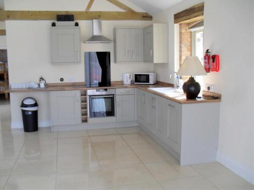 a kitchen with white cabinets and a table with a lamp at Foxes Den at Tove Valley Cottages in Towcester