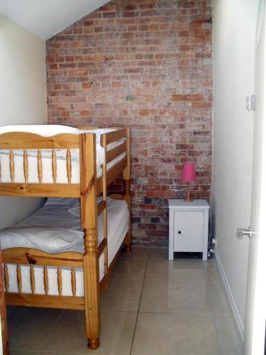 a room with two bunk beds and a brick wall at Foxes Den at Tove Valley Cottages in Towcester