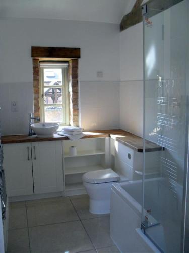 a white bathroom with a toilet and a sink at Foxes Den at Tove Valley Cottages in Towcester