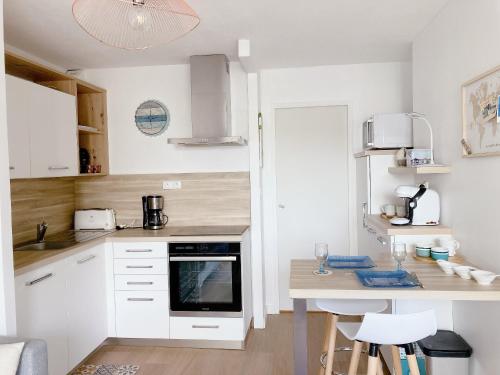 une cuisine avec des armoires blanches et une table avec des chaises dans l'établissement Nouveau * Ty Lévenez *pour 2 vacanciers * Parking, à Carnac