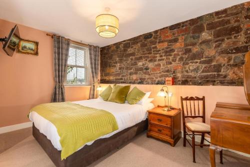 a bedroom with a bed and a brick wall at The Red Admiral Gosforth CA20 1BP in Seascale