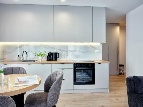 a kitchen with white cabinets and a table and chairs at A&W Apartament Zatoka Zwycięstwa - Rokosowo in Koszalin