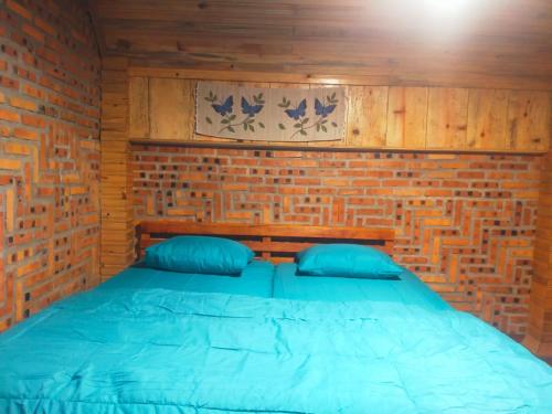 Cama en habitación con pared de ladrillo en Villa Cemara Siosar, en Kabanjahe