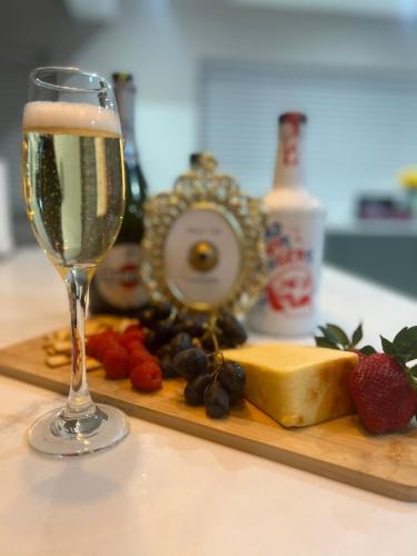 a glass of champagne next to a plate of cheese and berries at Brian’s Escape in Great Driffield