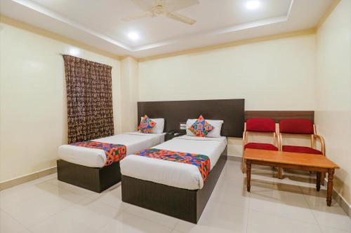 a bedroom with two beds and a table and chairs at FabHotel Champion Residency in Bangalore