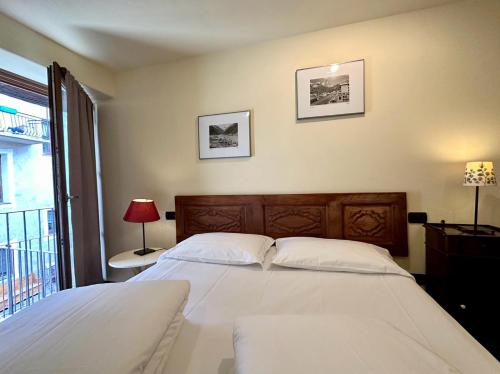 a bedroom with a large white bed and a window at Maison Rosset agriturismo, CAMERE, appartamenti e spa in Valle d'Aosta in Nus