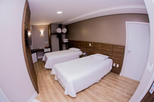 um quarto de hotel com duas camas e um espelho em Poente Hotel em São Lourenço do Oeste