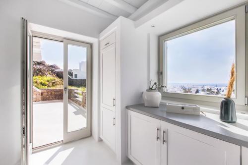 een keuken met witte kasten en een groot raam bij Breathtaking 6 Bed in Platis Gialos in Platis Yialos Mykonos