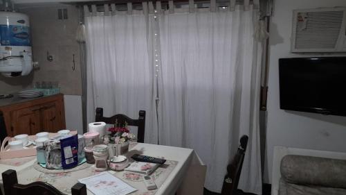 uma mesa de jantar com uma cortina branca e uma televisão em ALOJATE CATALEIA dep 1 EZEIZA PLENO CENTRO A 12 MINUTOS DE AEROPUERTO MINISTRO PISTARINI em Ezeiza