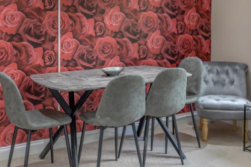 a table and chairs with a wall of roses at OPP B'ham - Freshly refurbished walls and carpets! BIG SAVINGS booking 7 days or more! in Marston Green