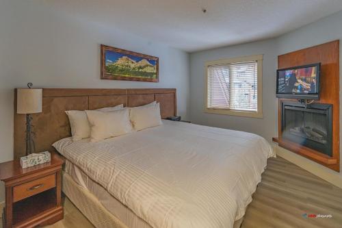 ein Schlafzimmer mit großem Bett und Kamin in der Unterkunft Solara Studio with Pool/Hot tub/Parking/Gym in Canmore