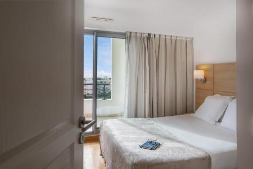 カーニュ・シュル・メールにあるNemea Appart Hotel Le Lido Cagnes sur Merのベッドと窓が備わるホテルルーム