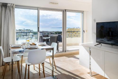 カーニュ・シュル・メールにあるNemea Appart Hotel Le Lido Cagnes sur Merのダイニングルーム(テーブル、椅子付)、大きな窓が備わります。