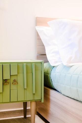 a green cabinet next to a bed with a white pillow at Casa Quattordici in Cesena