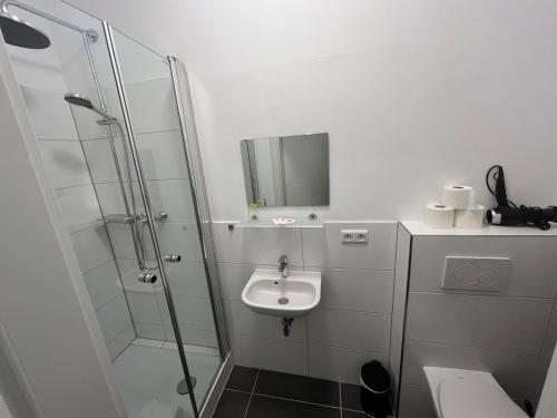 a white bathroom with a sink and a shower at Pension Donau in Hannover