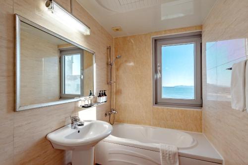 a bathroom with a sink and a tub and a window at Namiltte Resort in Sacheon