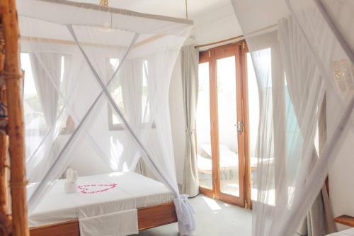 1 dormitorio con cama con dosel y ventana en Bukoba Villas - Olive - Private Pool, AC & Wi-Fi, en Nungwi