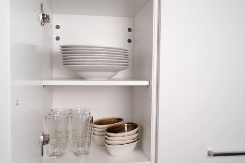 a white cabinet with plates and bowls and glasses at NEW modernes Loft im Zentrum von Deggendorf in Deggendorf