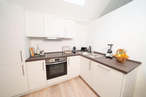 a kitchen with white cabinets and a counter top at NEW modernes Loft im Zentrum von Deggendorf in Deggendorf