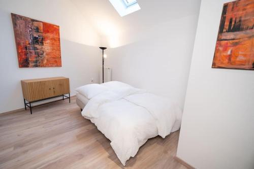 um quarto com uma cama branca e pinturas na parede em NEW modernes Loft im Zentrum von Deggendorf em Deggendorf
