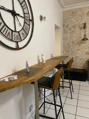 une grande horloge sur le mur dans une pièce avec des chaises dans l'établissement Chaleureux meublé 3 étoiles 40m2, à Aix-les-Bains