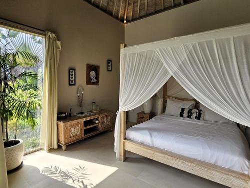 una camera con letto a baldacchino e ampia finestra di Villa Bodhi Kulture - Huge 4BR Luxury Villa for families & groups in Canggu - Bali a Canggu