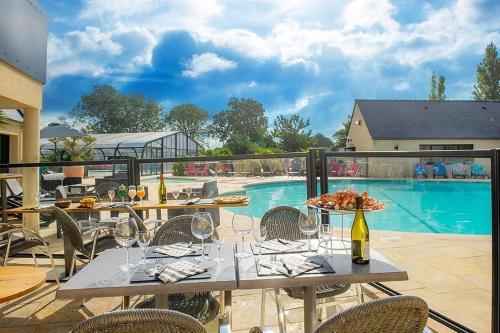 - une table avec des verres à vin à côté de la piscine dans l'établissement mobil home 6 pers camping 4 étoiles domaine de la pommeraie tregunc bretagne, à Trégunc