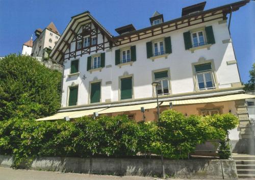 a large white building with a castle in the background at Concept Hotel Landhaus - Digital Hotel in Burgdorf