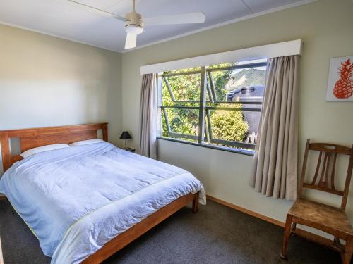 ein Schlafzimmer mit einem Bett und einem Fenster in der Unterkunft Godwit Cottage - Pākawau Beachfront Holiday Home in Pakawau