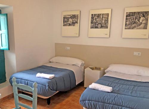 a room with two beds and a chair and pictures on the wall at ALOJAMIENTO NO ACTIVo in Moclín