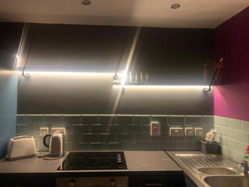 a kitchen with a stove and a sink with lights at Comfortable 1-Bed Apartment in Liverpool Sleeps 4 in Liverpool