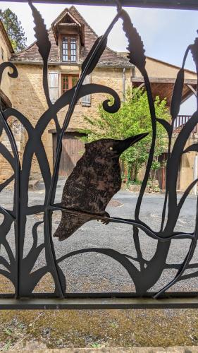 un oiseau noir sur une porte métallique devant une maison dans l'établissement Kingfisher Cottage, à Castelnaud-la-Chapelle