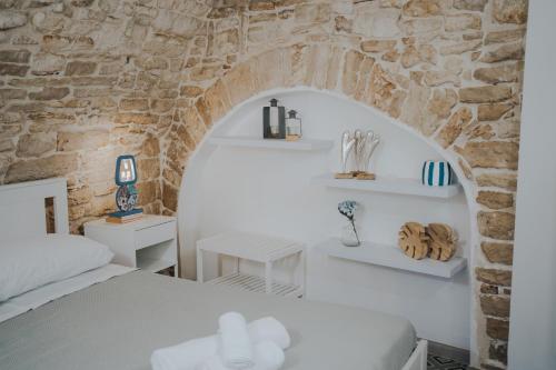 um quarto com uma cama e uma parede de pedra em PUGLIA MIA em Giovinazzo