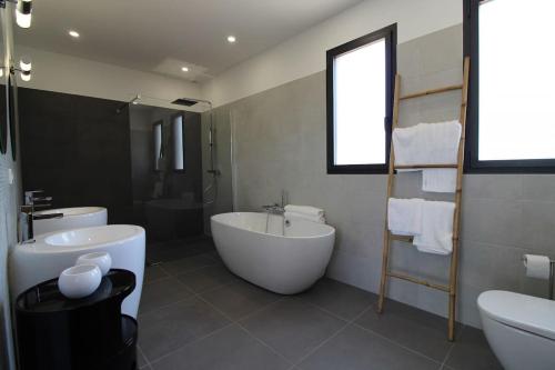 une salle de bain blanche avec une baignoire et un lavabo dans l'établissement Villa Porra avec piscine 8 pers vue montagne, à Porto-Vecchio