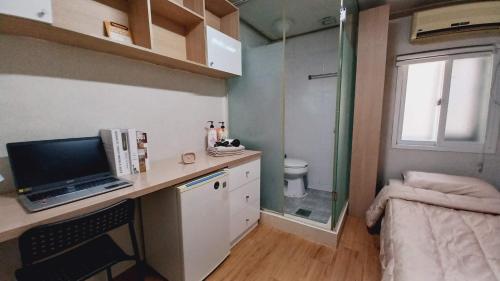 a small room with a desk with a television and a bed at Haechi Stay GuestHouse - For foreigners only in Seoul