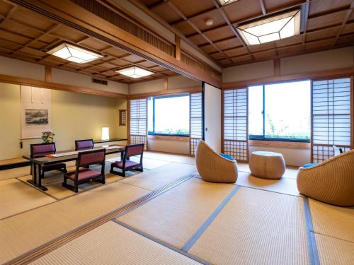 a large room with a table and chairs and windows at Hotel Fukiageso in Kagoshima