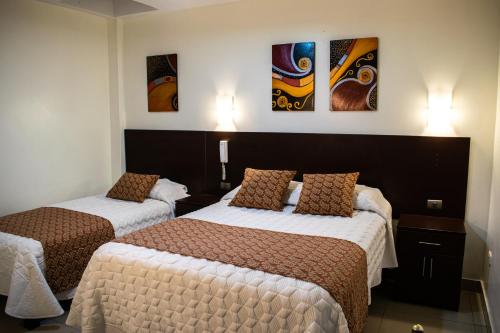 dwa łóżka w pokoju hotelowym z obrazami na ścianie w obiekcie Hotel Hatunkay Chaclacayo w mieście Lima