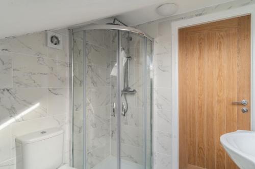 a bathroom with a shower with a toilet and a sink at Refined Comforts for Two Room 5 in Manchester