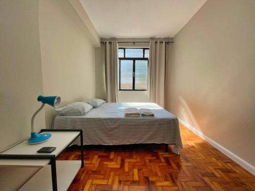 a bedroom with a bed and a desk and a window at Apartamento 2 QTS Excelente Localização - EV05 in Maringá