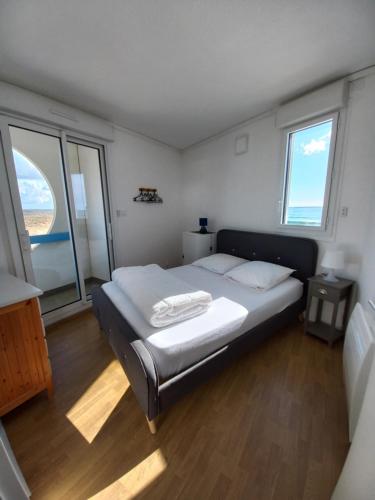 une chambre avec un lit dans une pièce avec des fenêtres dans l'établissement Balcon sur mer, à Saint-Gilles-Croix-de-Vie