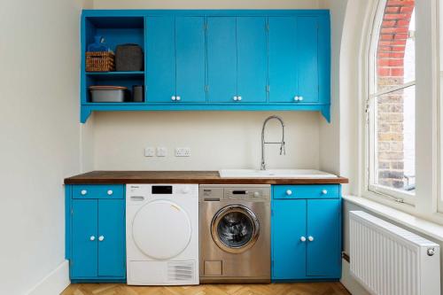 a laundry room with blue cabinets and a washing machine at Veeve - Richmond Accents in London