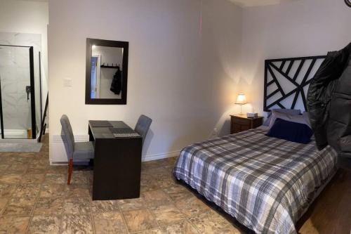 a bedroom with a bed and a desk and a mirror at Studio entièrement privé aux quatre vents in Lac-Mégantic
