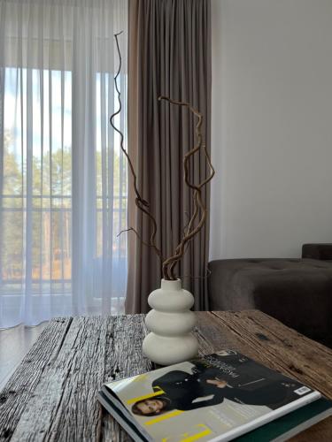 una sala de estar con una mesa con un jarrón. en Saulės Tako apartamentai, en Druskininkai