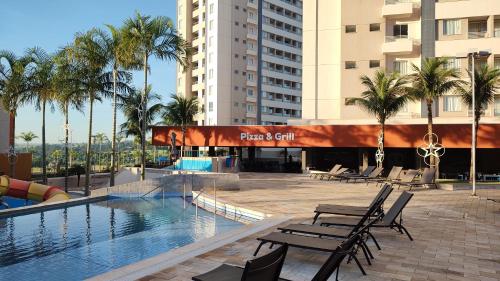 a pool at a hotel with chairs and palm trees at Solar das Águas - Resort Em Olimpia - Ap 2 quartos in Olímpia