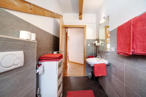 y baño con lavabo, espejo y toallas rojas. en Fröhlichhof Wohnung Panorama en Lagundo